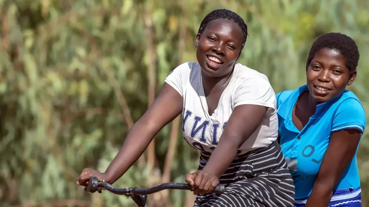 Two teenage girls in Malawi, riding a bicycle