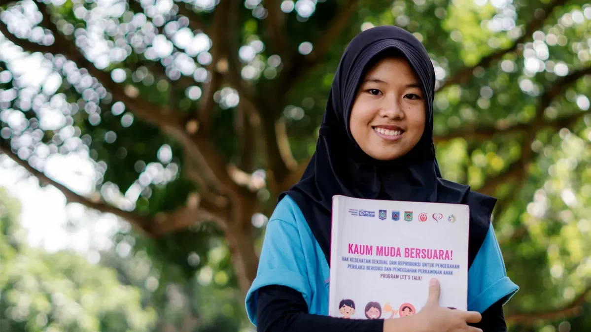 Adiana, 13, holding an education pack about child marriage, distributed by Plan International