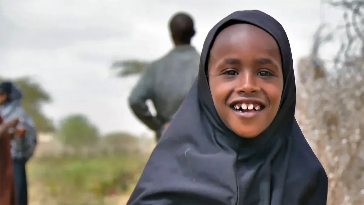 A young girl wearing a hijab smiling at the camera.