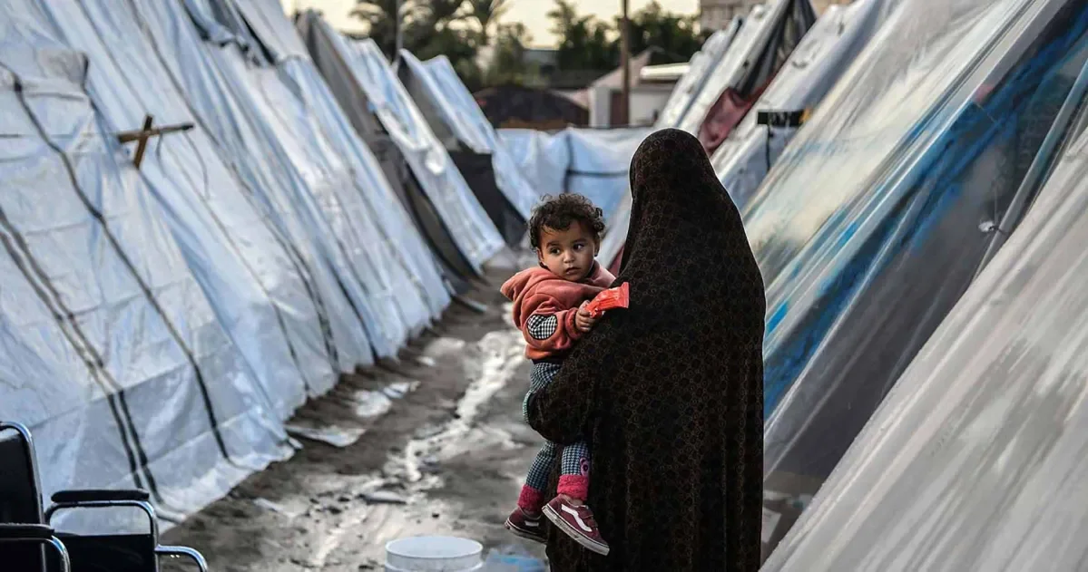 A Palestinian woman holding her child in a refugee camp