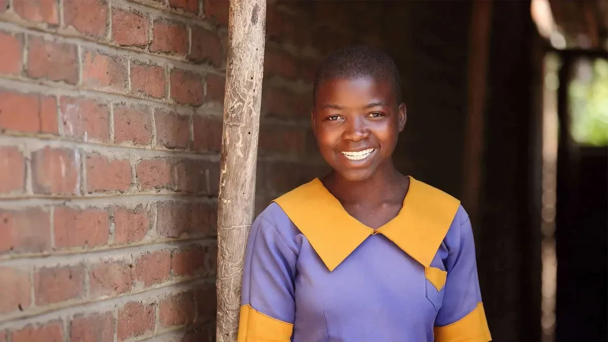 Irene, 13, standing in front of brick wall wearing her school uniform