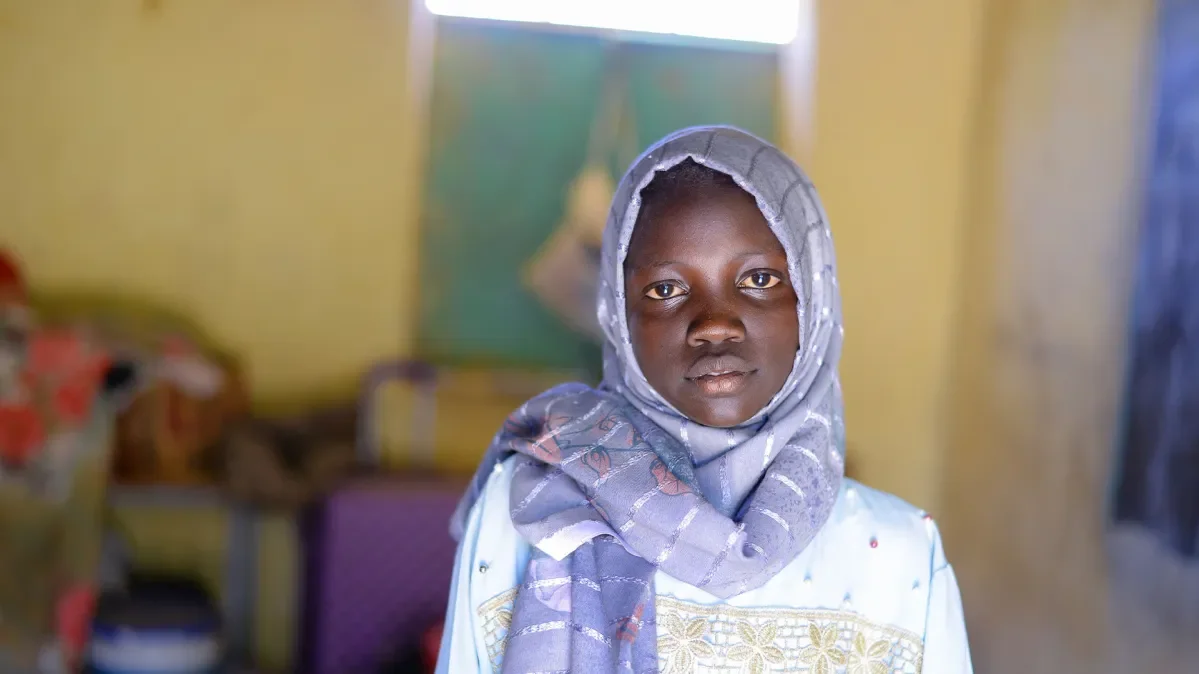 Muna looking at camera with blurred school background behind her