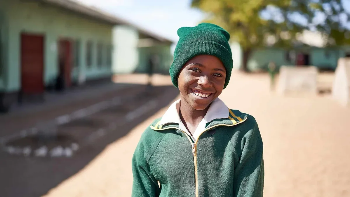 Kimberly standing outside of school smiling at camera. Background is out of focus