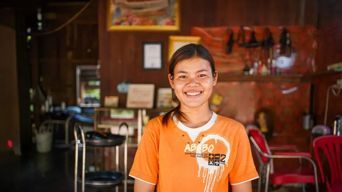 Sam Phou standing in her beauty salon smiling at camera. The salon background is out of focus