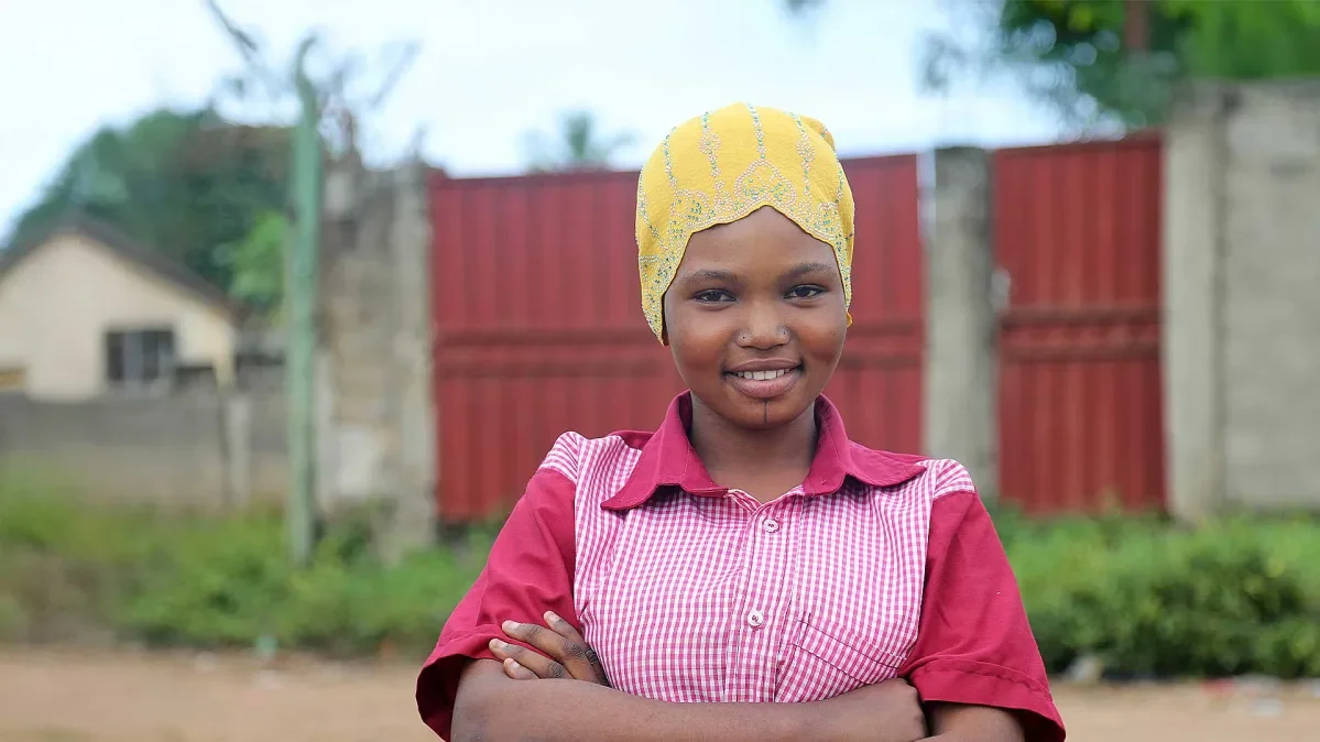 Roumana standing outside with arms crossed smiling at camera