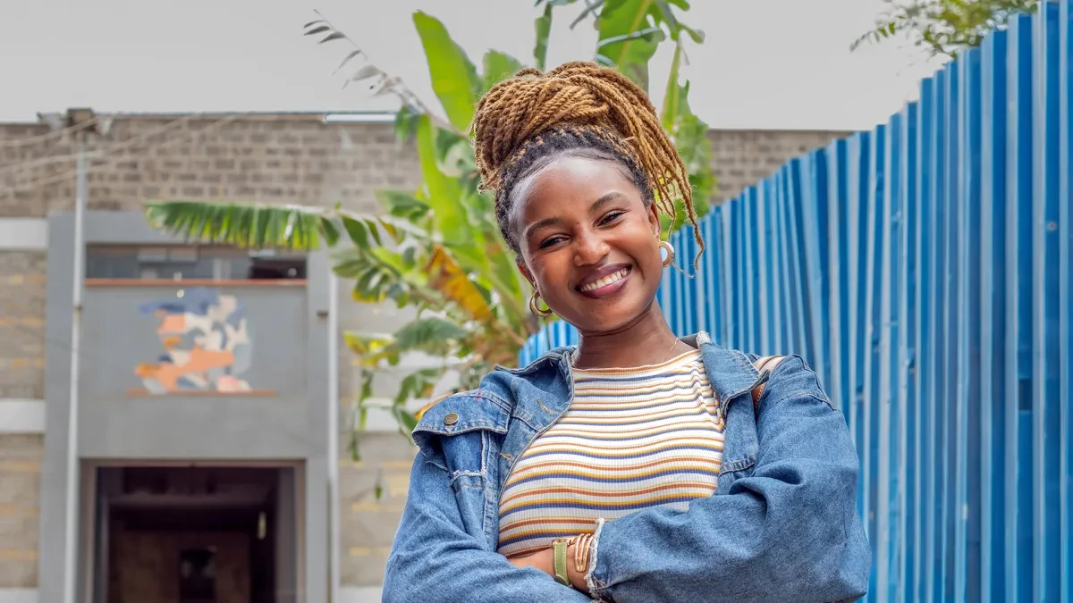 Latifah stands with folded arms. She is smiling at the camera.