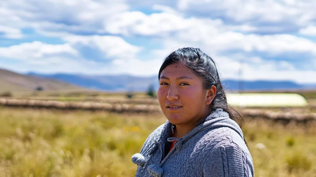 Geovana standing in field with arms out in front of her gesturing no to patriarchy