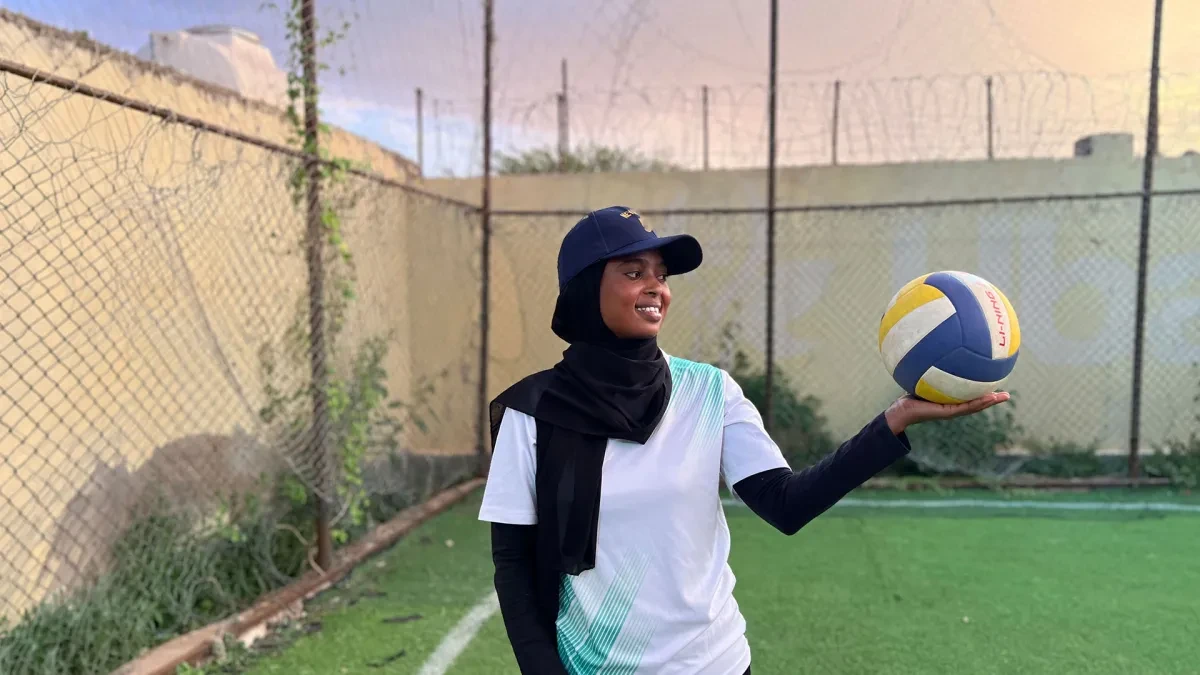 Hanah on a football pitch holding a football in one hand