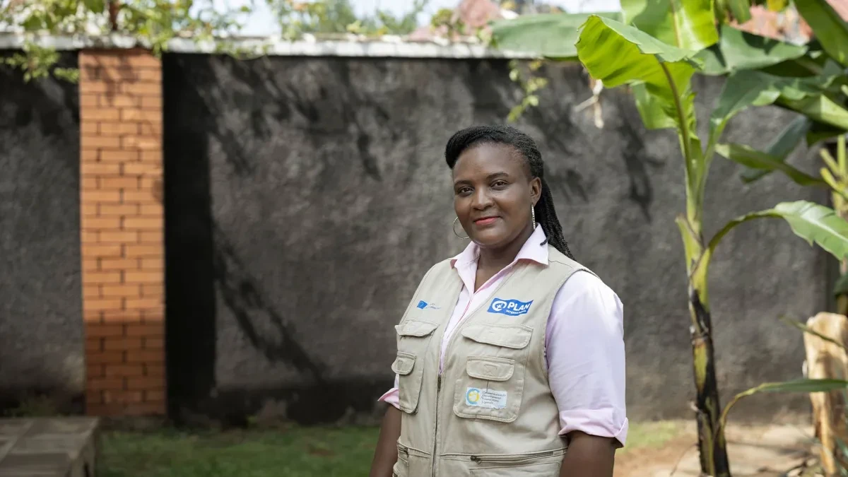 Christine standing outside wearing Plan International branded uniform. 