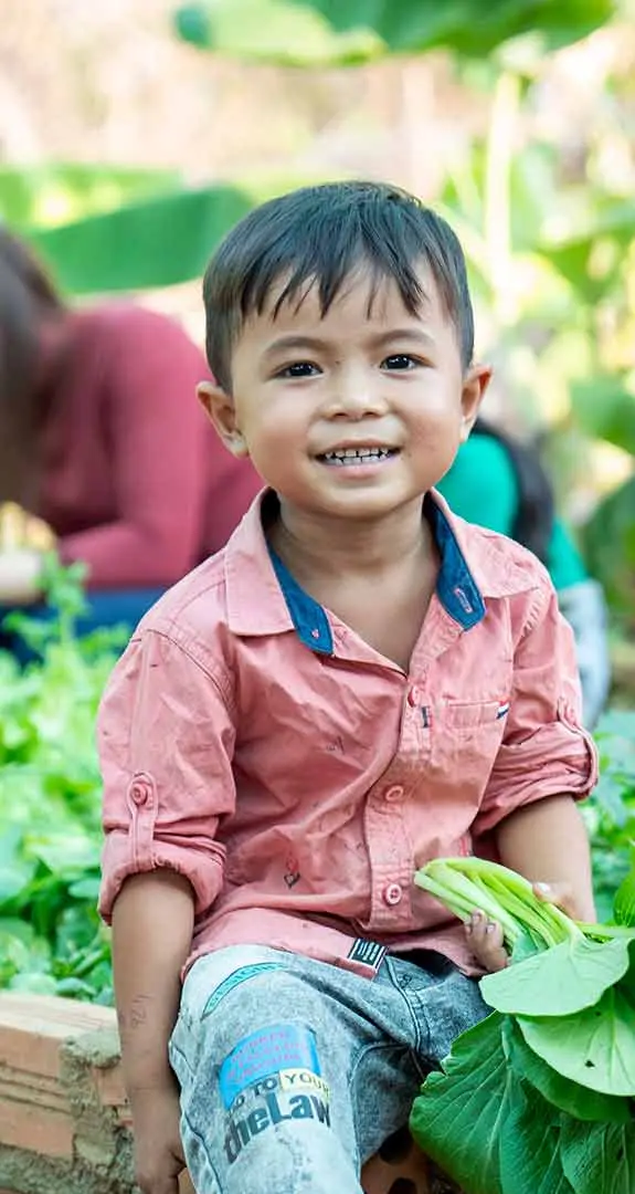 Mai, 3, in the community garden set up by Plan International