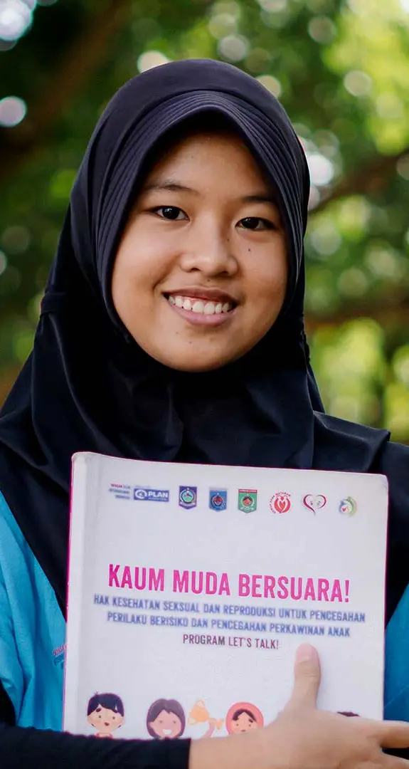 Adiana, 13, holding an education pack about child marriage, distributed by Plan International