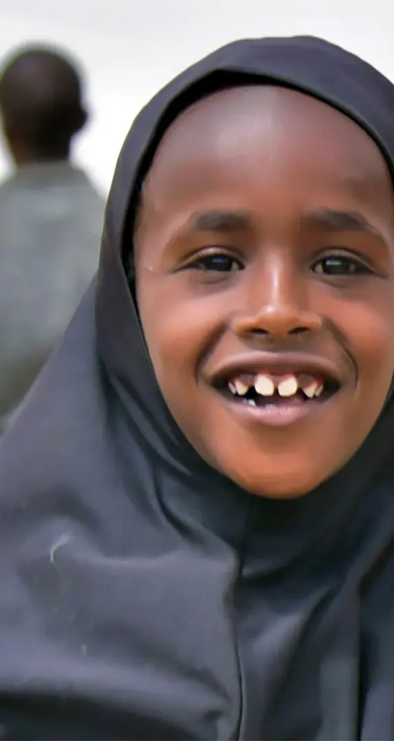 A young girl wearing a hijab smiling at the camera.