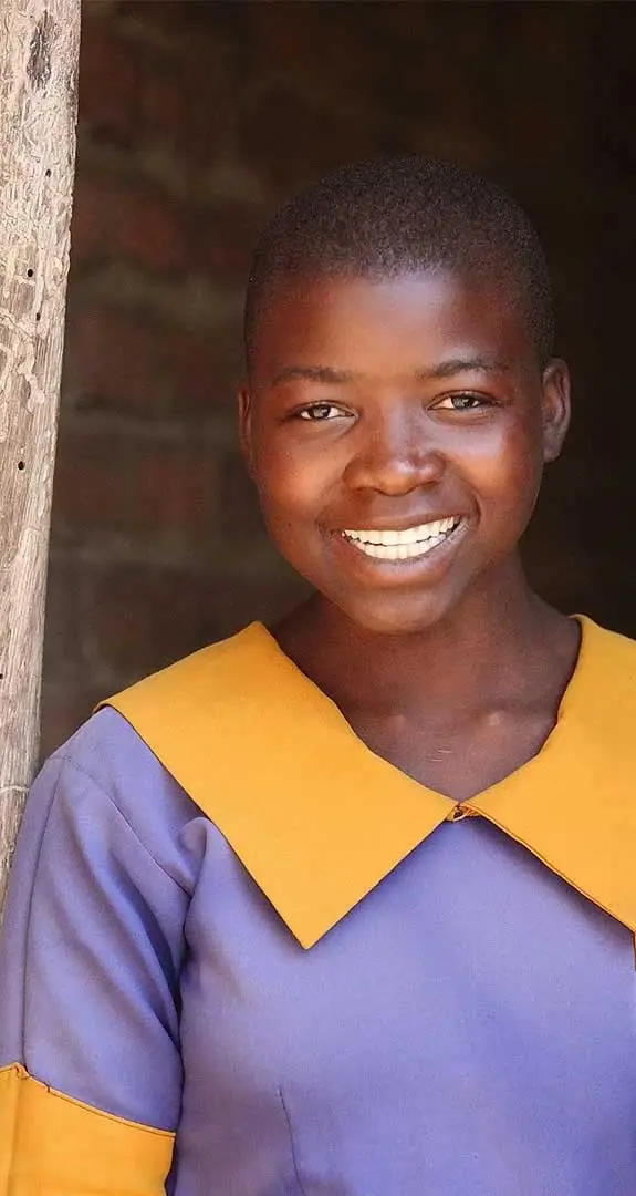 Irene, 13, standing in front of brick wall wearing her school uniform
