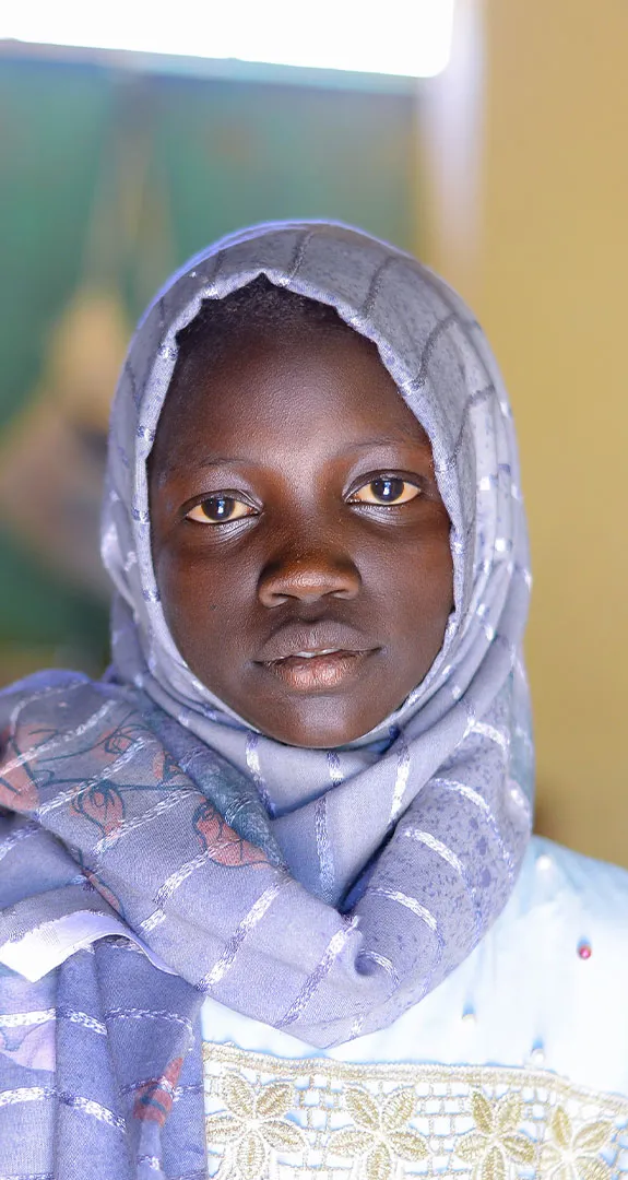 Muna looking at camera with blurred school background behind her