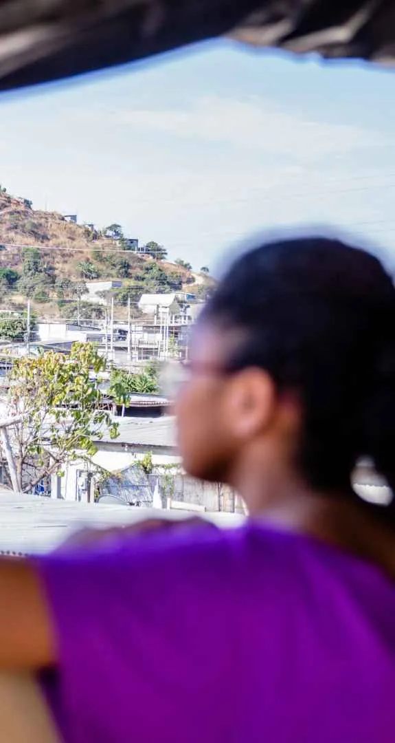 A girl in Ecudaor looking out over a town from a balcony