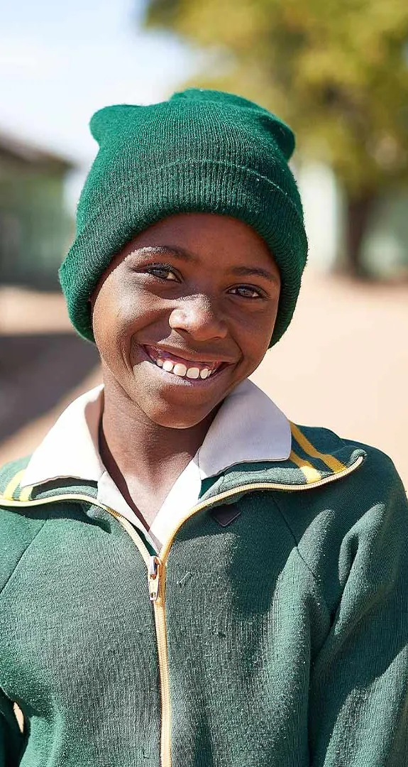 Kimberly standing outside of school smiling at camera. Background is out of focus