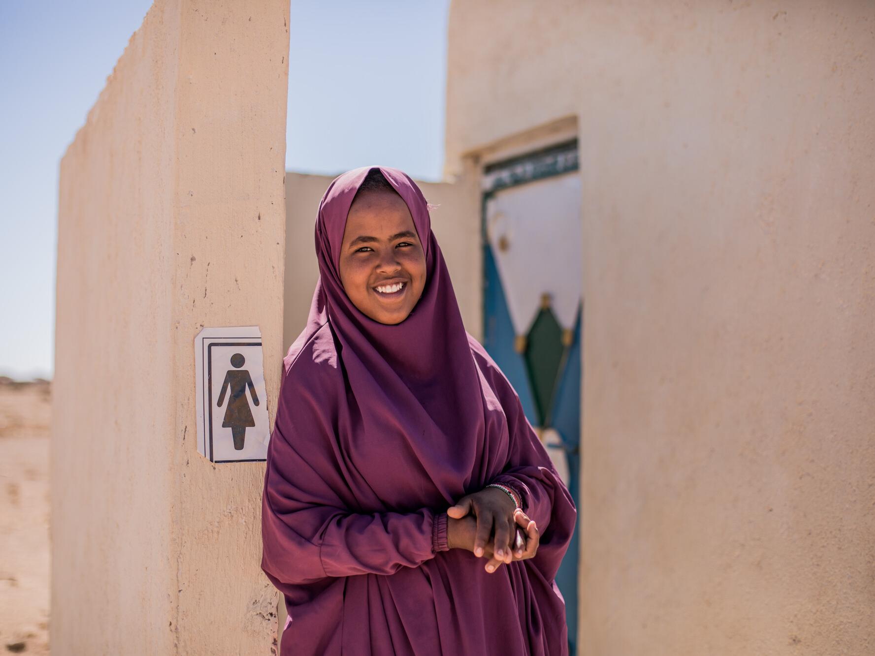 Hamda, 15, standing outside the new toilet facilities built by Plan International in Somalia