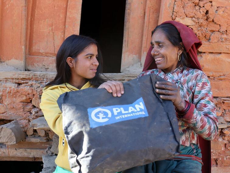 Sarita with her mum in Nepal, holding a dignity kit distributed by Plan International.