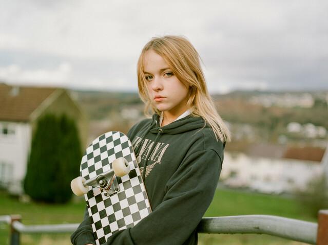 Scarlett, 12, holding a skateboard standing outside near her home town in Wales