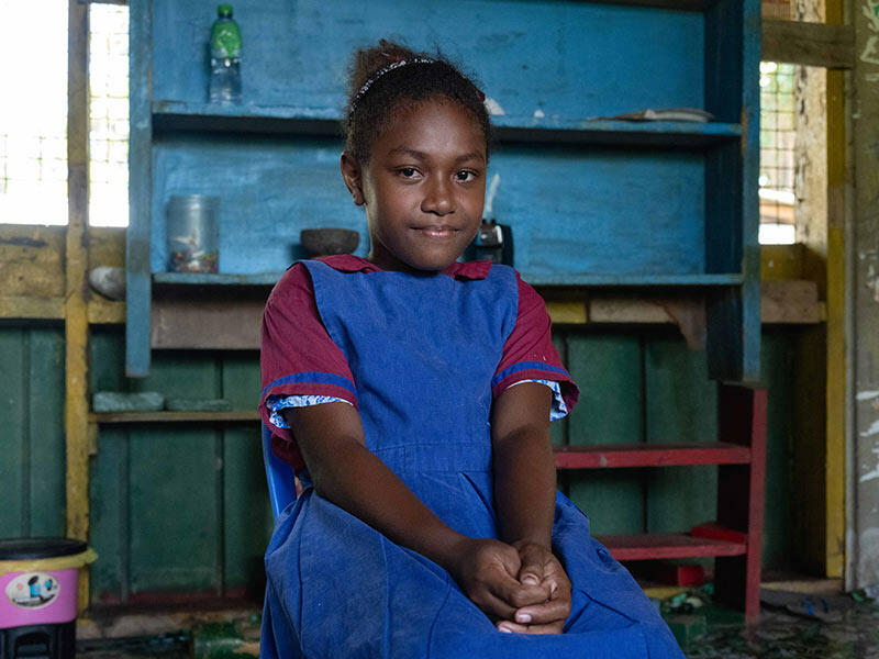 School girl sits with hand hands in her lap