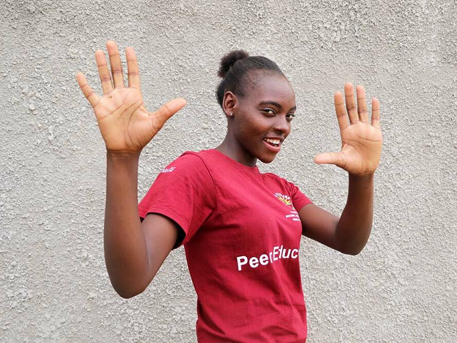 Faith, 19, posing with her hands up and smiling at the camera
