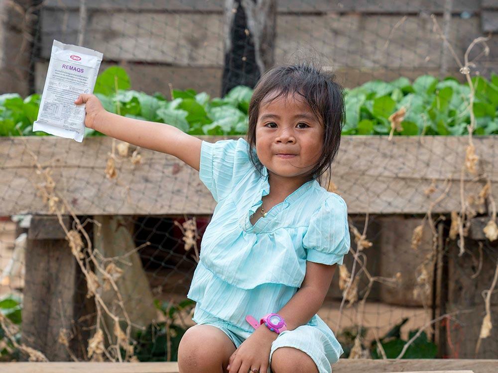Bundorb, 4, in Cambodia holds up a pack of supplementary food full of nutritional goodness to help her grow.