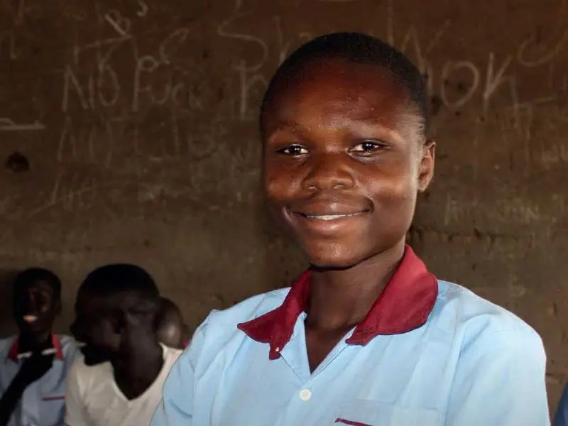Girl smiling at camera standing in classroom