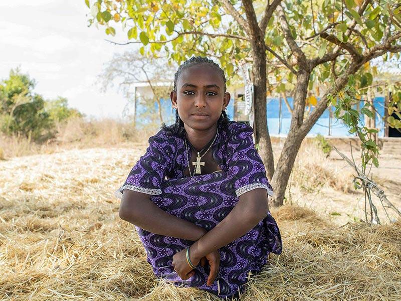 A girl call Woyzer sitting outside under a tree