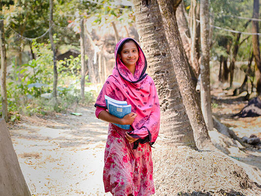 Marzia, 17, carrying books home from a new learning centre in Bangladesh. 