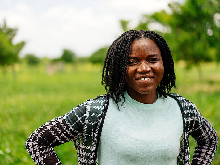 Doris, 27, standing in a field on a farm in Ghana