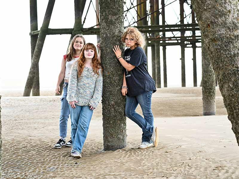 three girls look at the camera on a beach in Blackpool