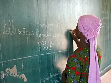 Mariam, 18, writing on a blackboard in her school classroom in Mali