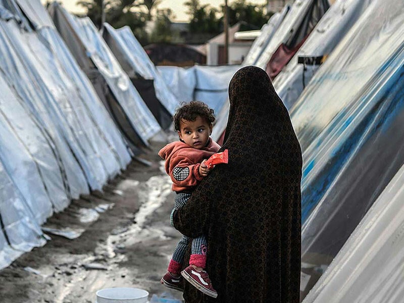 A woman holds a child in war torn Gaza