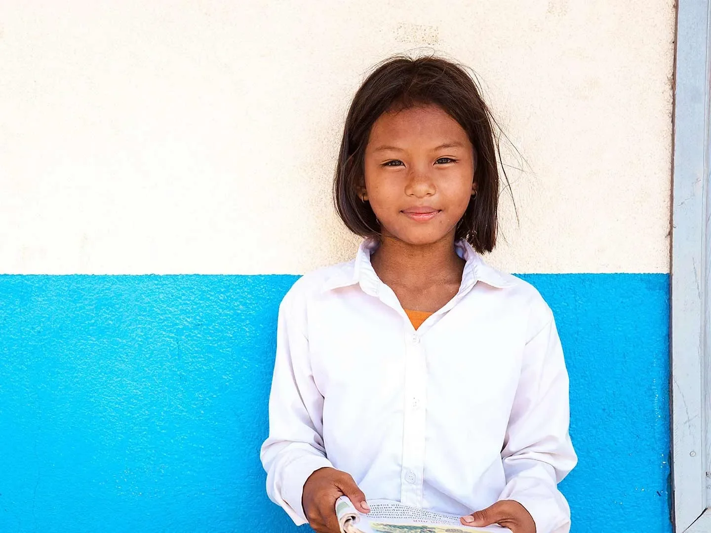Muta, 11, standing in front of a white and blue wall.