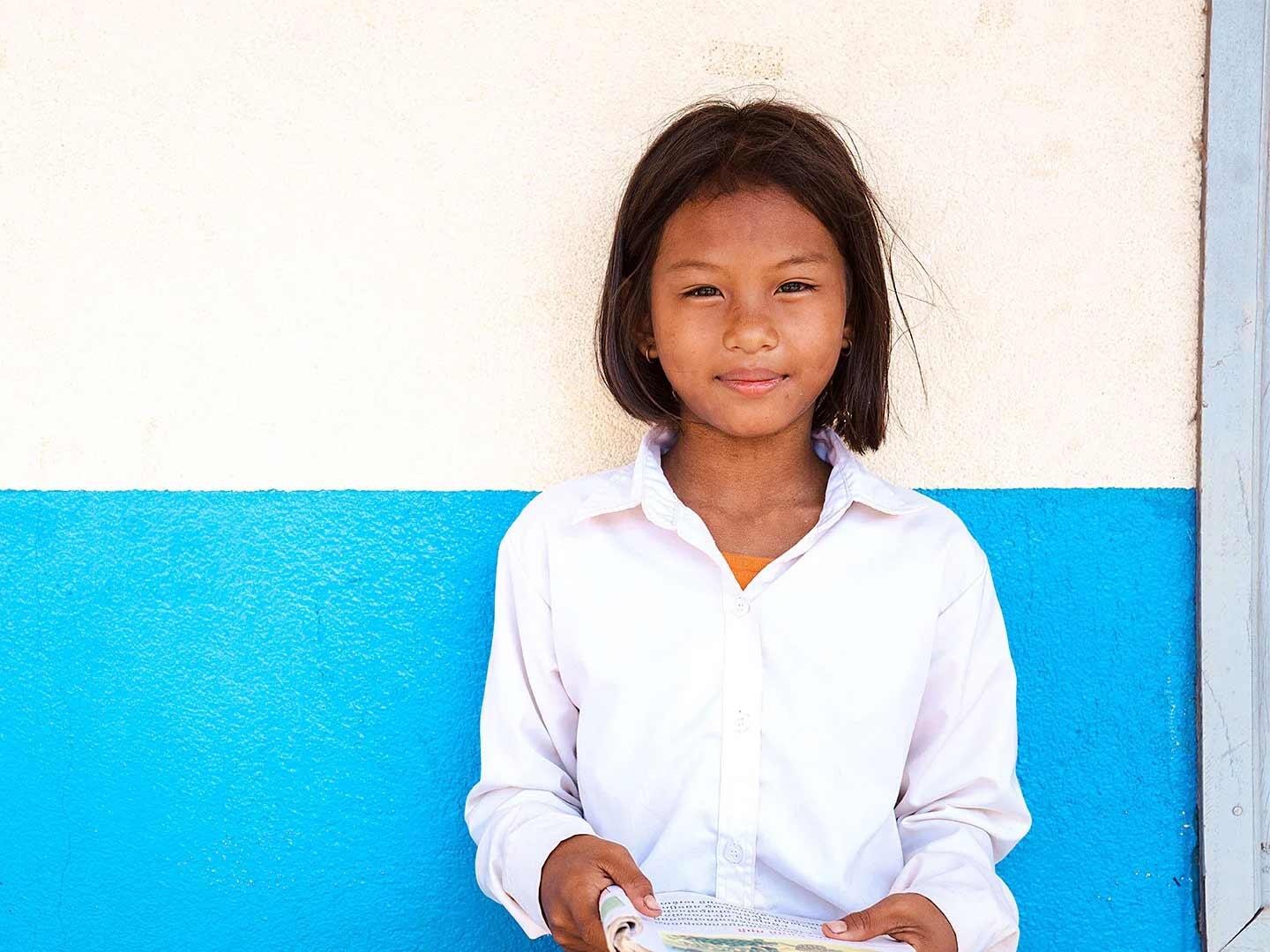 Muta, 11, standing in front of a white and blue wall.