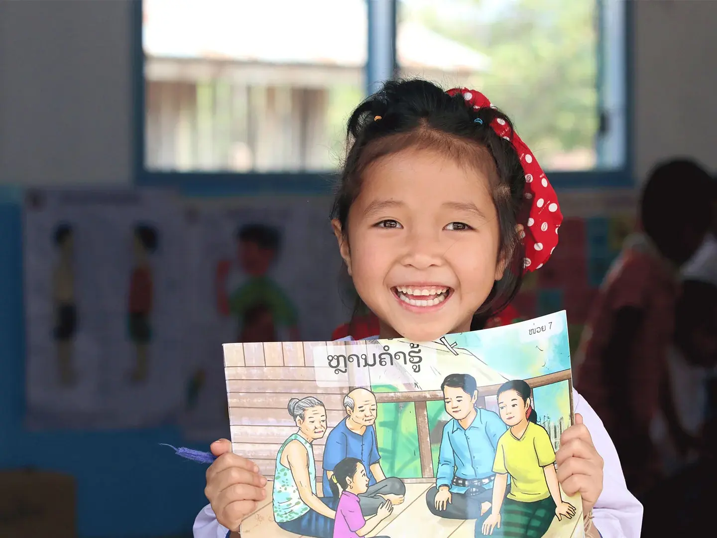 A girl holds a picture and smiles at the camera