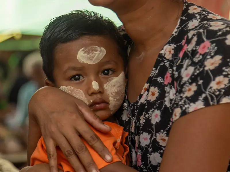 Yaza* sits with his mother, Kyi*, under a makeshift shelter in a village in the Mandalay region following the earthquake in Myanmar