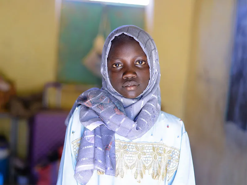 Muna looking at camera with blurred school background behind her