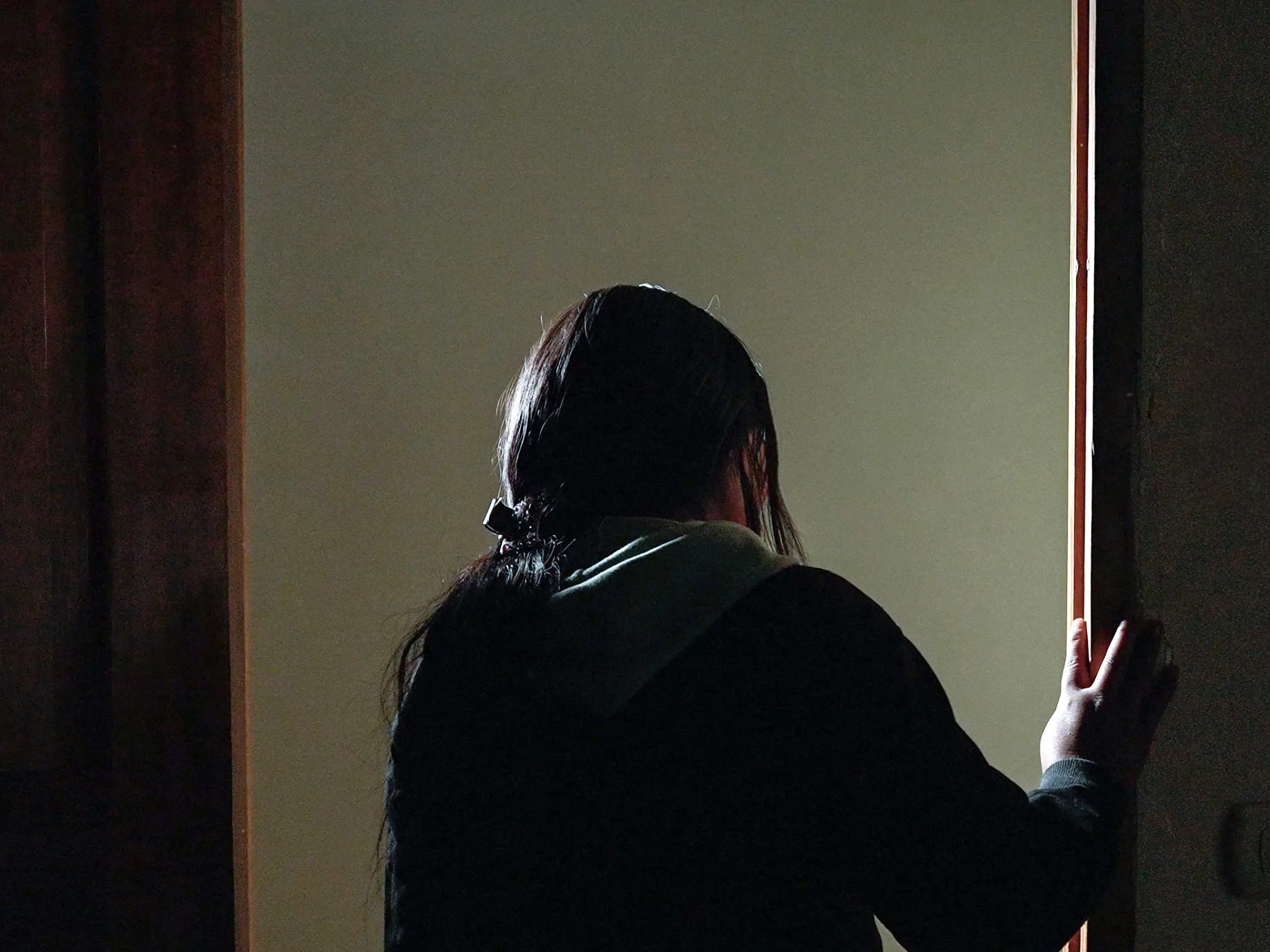 Flor*, 20, who was forced into an abusive union stands at the doorway of her home in Peru.