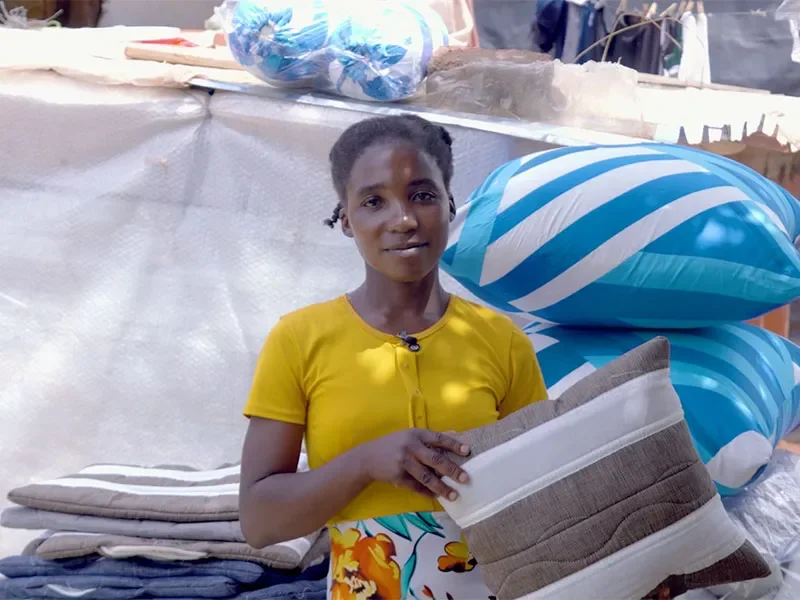 MItais holding cushion with cushions behind her.