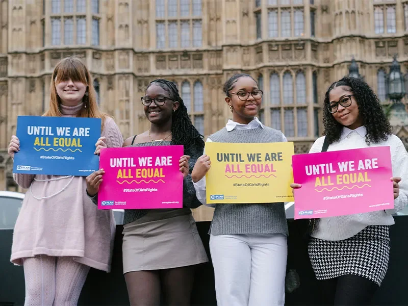 4 Youth Advisory Panel members standing outside parliament with signs saying 'until we are all equal'