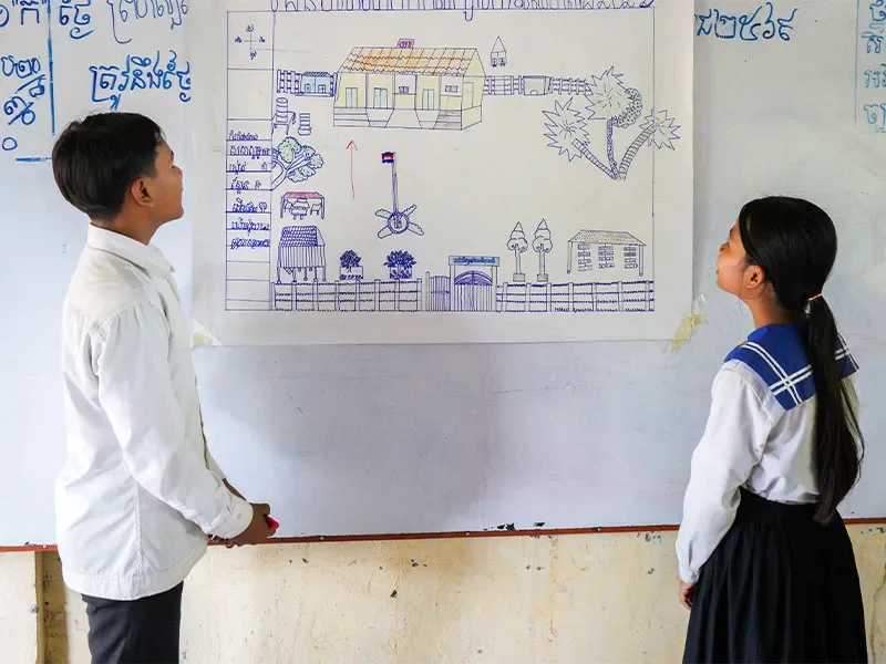 Boy and girl looking at drawing on whiteboard in classroom.