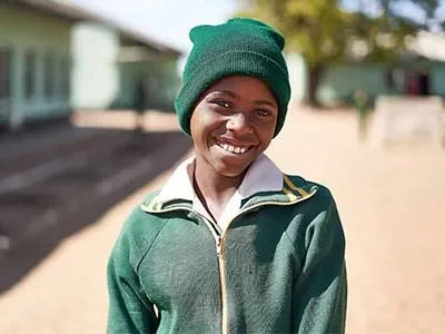 Kimberly standing outside of school smiling at camera. Background is out of focus