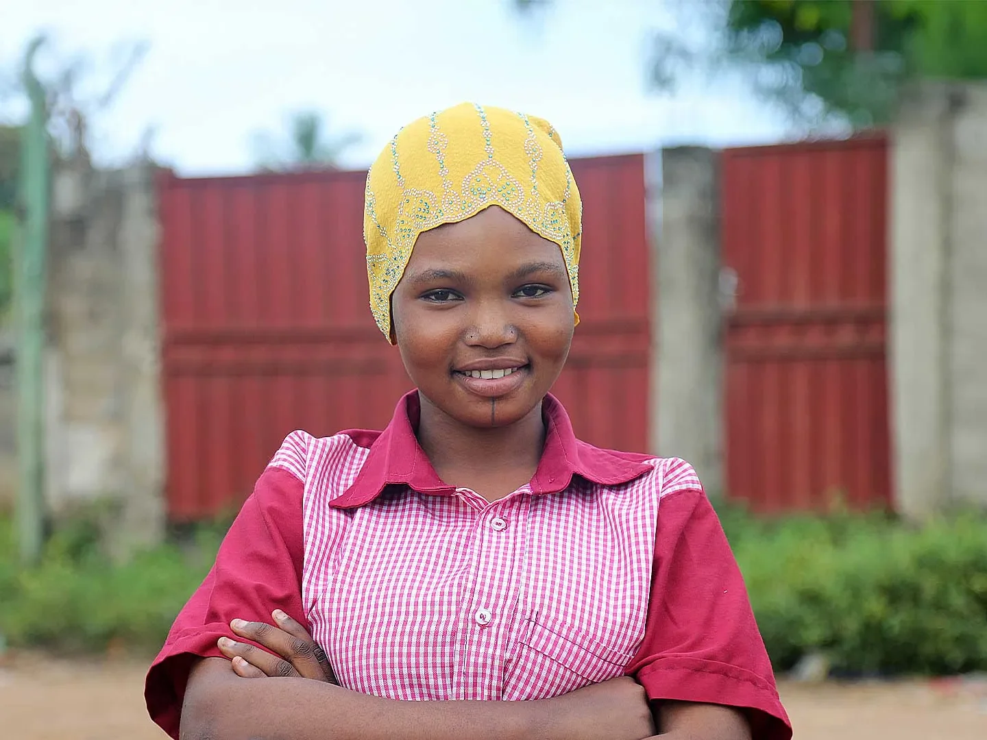 Roumana standing outside with arms crossed smiling at camera