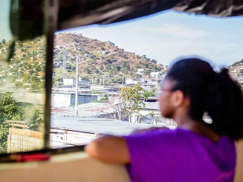 A girl in Ecudaor looking out over a town from a balcony