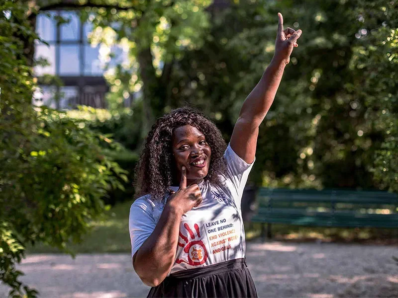 Racheal, 26, pointing her finger to the sky and smiling at the camera