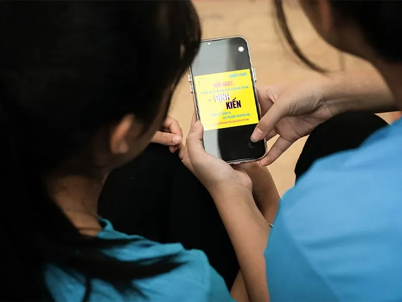 Backs of two girls heads looking at a petition on a phone.