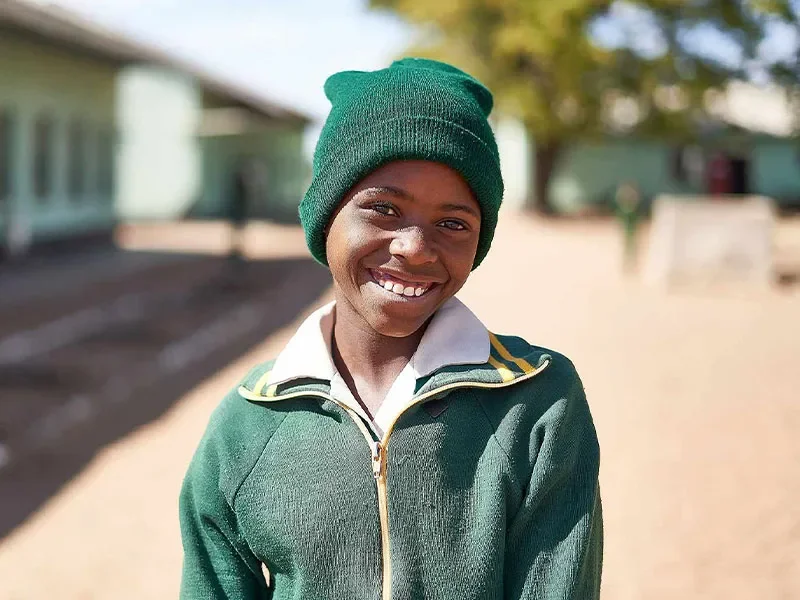 Kimberly standing outside of school smiling at camera. Background is out of focus