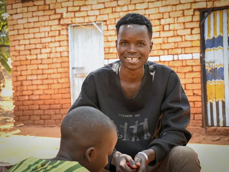 Traifon, 19, is sitting outside. He is talking to another boy as part of the Champions of Change group.