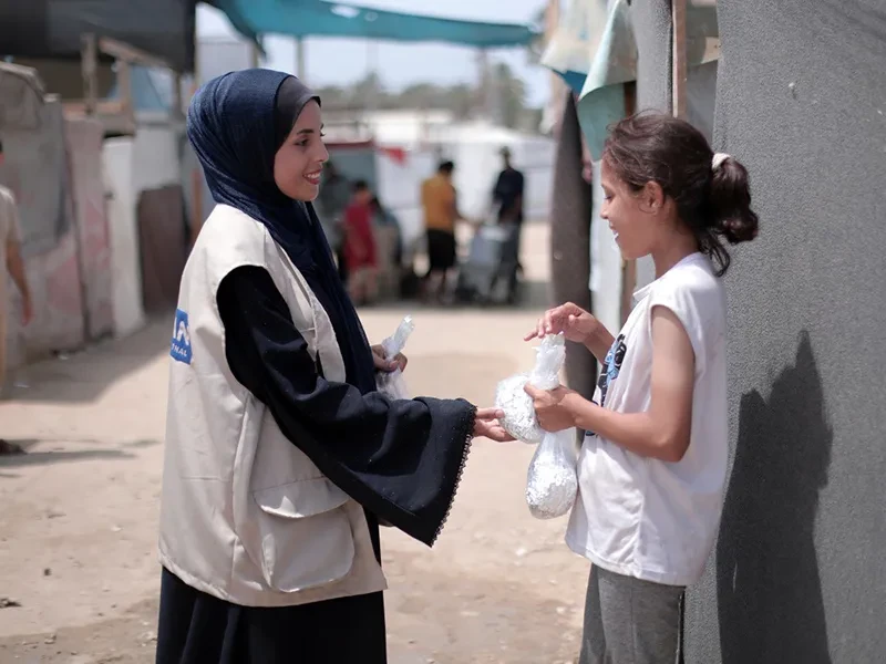 A girl in Gaza receives food from an aid worker. 